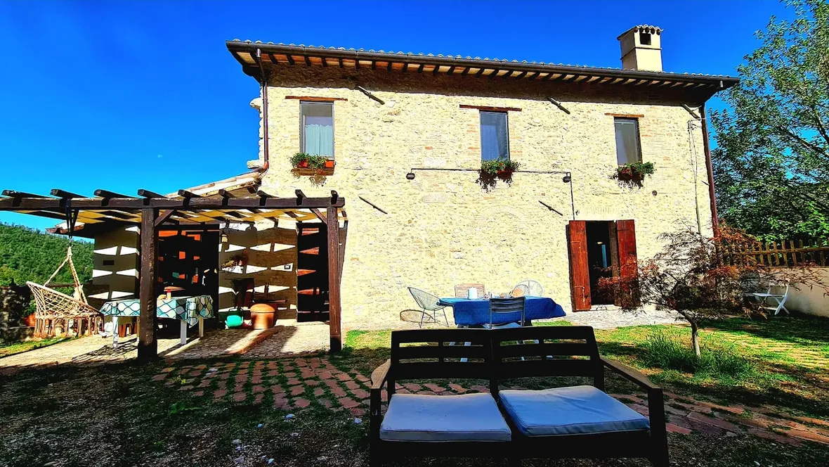La casa in pietra vista dal prato, con la valle sullo sfondo